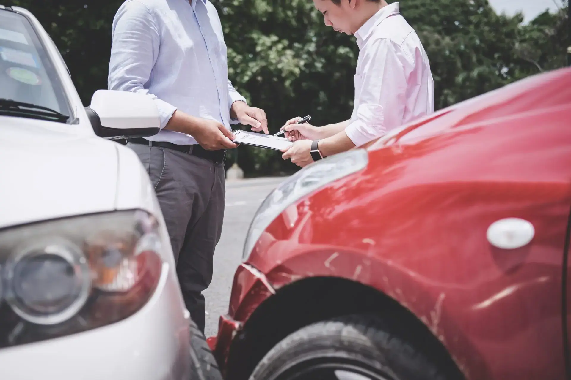 Two men exchanging information in front of their damaged cars