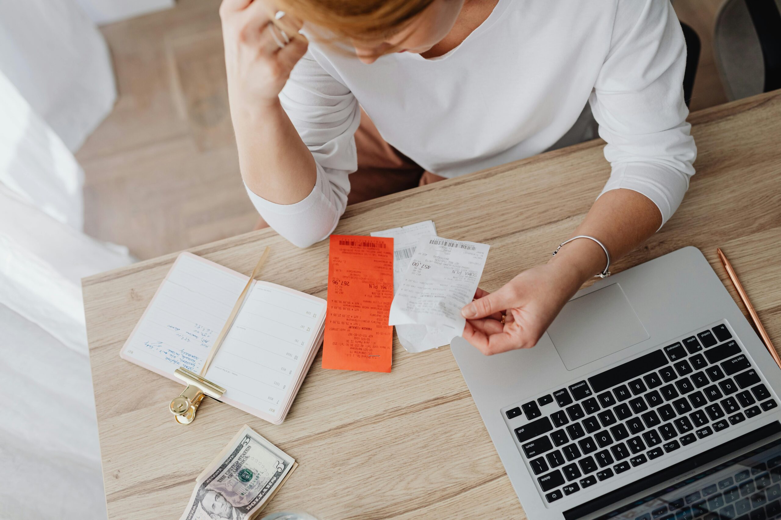 Woman looking at receipts and money in front of her laptop